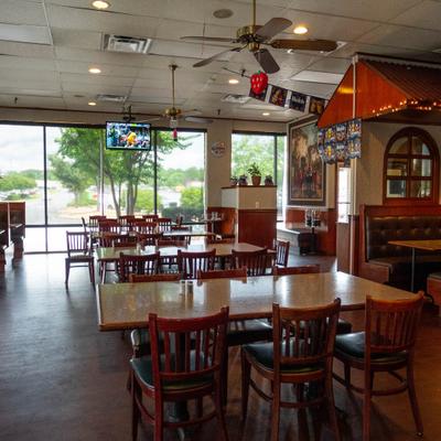 An indoor restaurant dining room featuring wooden tables, chairs, and cushioned booths.
