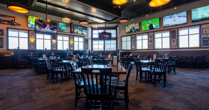 Spacious and cozy sports bar dining area with TVs on the walls