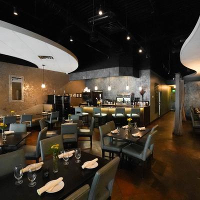 Dining area with tables set for guests and a bar with stools.