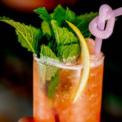 Naked And Famous garnished with mint leaves, lemon peel and a pink straw.
