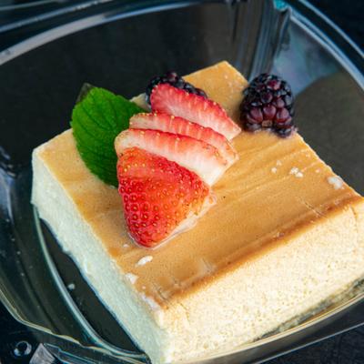 Flan garnished with strawberry slices, blackberry and a mint leaf.