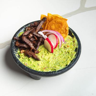 Guacamole with grilled steak, served with tortilla chips, sliced radish and onion.