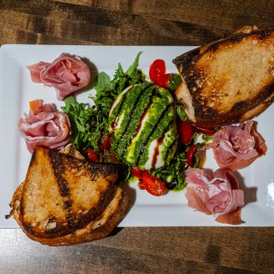 Burrata with prosciutto, cherry tomatoes, pesto aioli, balsamic glaze, and sourdough.