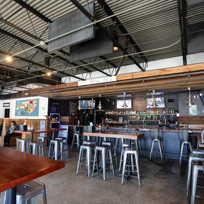 Interior featuring a well-stocked bar, high-top tables, and TVs.
