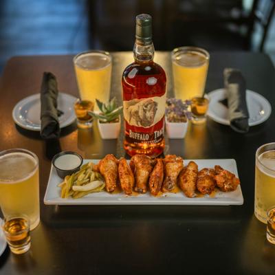 Smoked, honey-glazed wings served alongside pickled celery, ranch, beers, and bourbon shots.