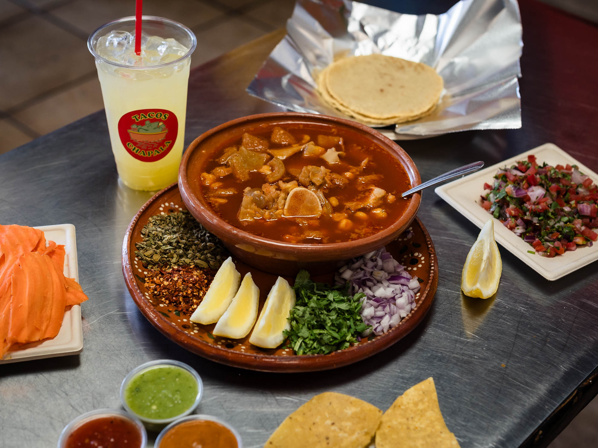 Menudo Mexican soup served with tortillas, lemon and a lemonade