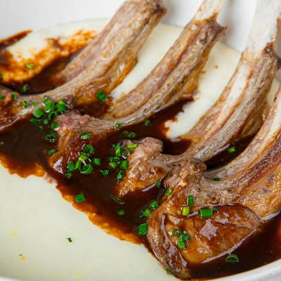 Seared lamb lollypops atop white creamy cheddar cheese grits and veal demi sauce.