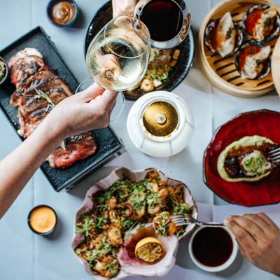 Assorted dishes displayed on a set table, guest holding a glass of wine.