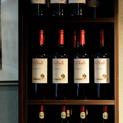 Dark wood shelving unit stocked with red wine bottles.