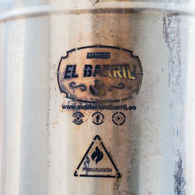 El Barril stainless steel vertical barrel charcoal smoker grill.