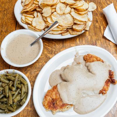 Chicken-fried steak smothered in gravy, served with green beans and potatoes.