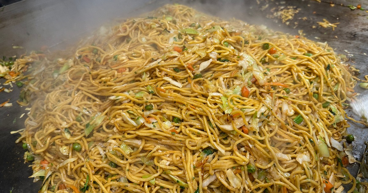 Stir-fried noodles steaming on a flat grill