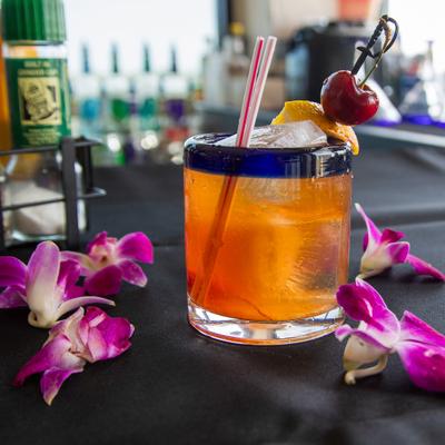 Old Fashioned cocktail garnished with orange peel and a cherry on a pick.