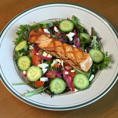 Grilled salmon salad with cucumber, tomato, and greens.