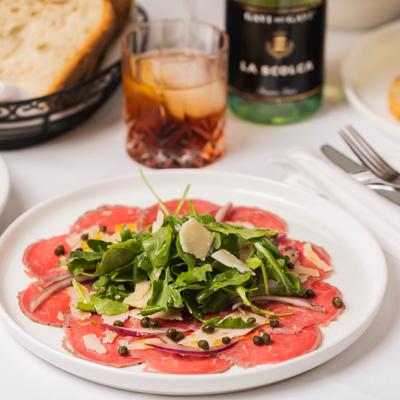 Beef carpaccio topped with arugula, Parmesan, and capers.
