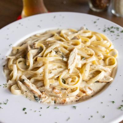 Chicken Alfredo pasta served on the plate, close-up.
