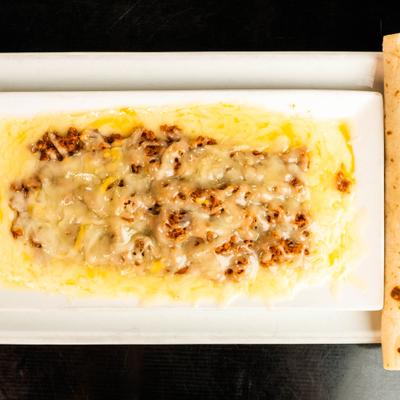 Queso Flameado served on rectangular with tortilla on the side.