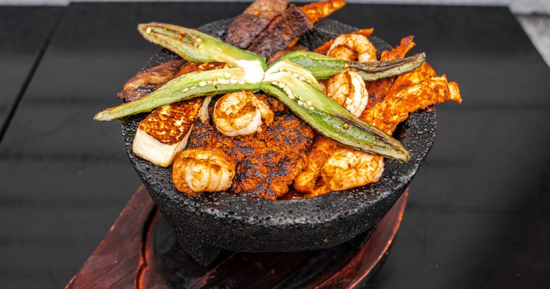 Molcajete featuring various grilled meats, seafood, and vegetable