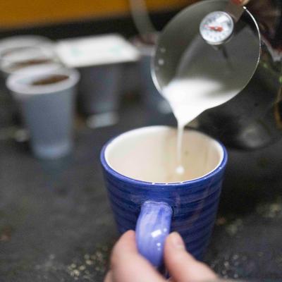 Milk being poured into cup from a pitcher.