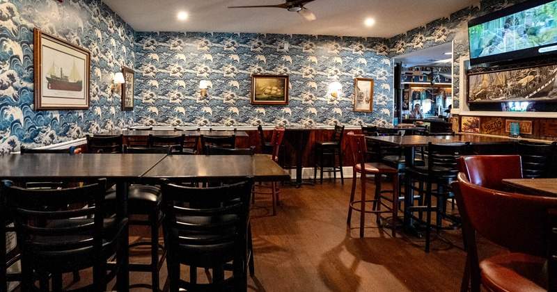 Interior of a nautical-themed restaurant featuring wave-patterned wallpaper, wooden floors