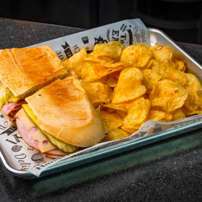 Cuban Sandwhich served on a tray with a side of potato chips.