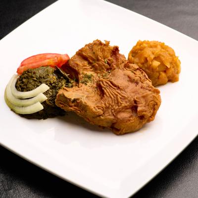 Pork chop served with a side collard greens and mashed sweet potatoes.