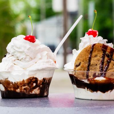 Two ice cream sundaes topped with whipped cream, cherries, and chocolate sauce.