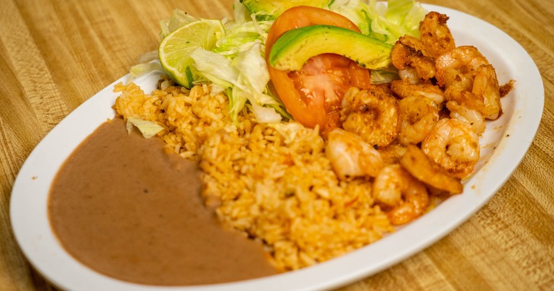 Shrimp with rice, beans, lettuce, tomato, avocado, and lime slices