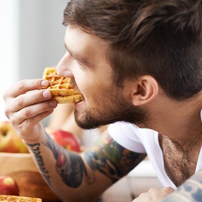Person eating waffle at the table.
