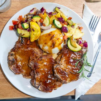 Bourbon pork chops, mashed potatoes topped with gravy, and colorful grilled vegetables.
