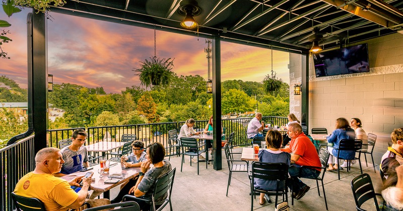 Covered seating area on a terrace, guests sitting and enjoying drinks