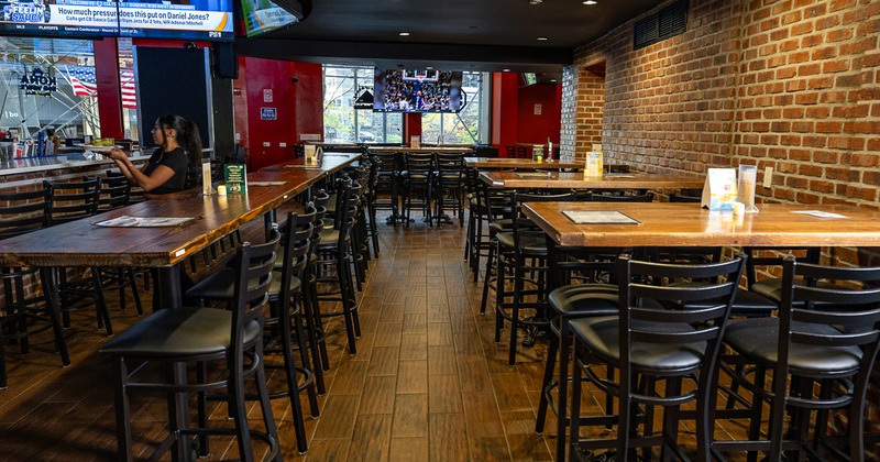 Sports bar seating with brick wall, bar area and high-top tables