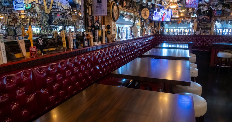 Interior of a pub with a long wooden table, burgundy leather seating, and decorative bar memorabilia