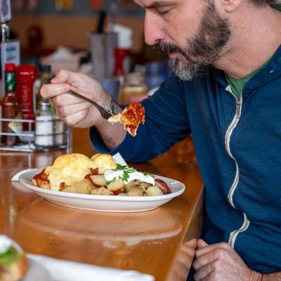 A patron eating poached egg Benedict.