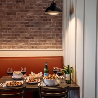 Interior, banquette seating and a dining table with served meals and red wine.
