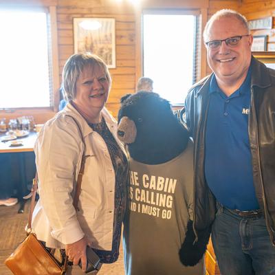 A couple of guests posing with a bear mascot in the dining setting.