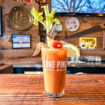 Bloody Mary garnished with a celery, a lemon wedge, a cherry tomato and a fried chicken wing.