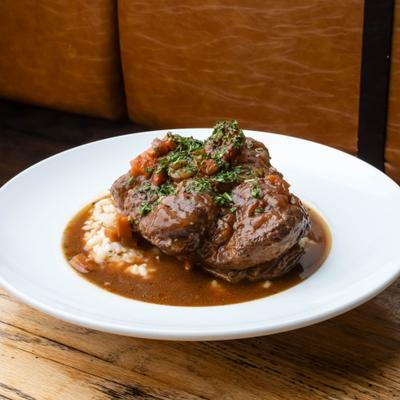 Osso Buco covered in a rich gravy, served on a bed of rice.