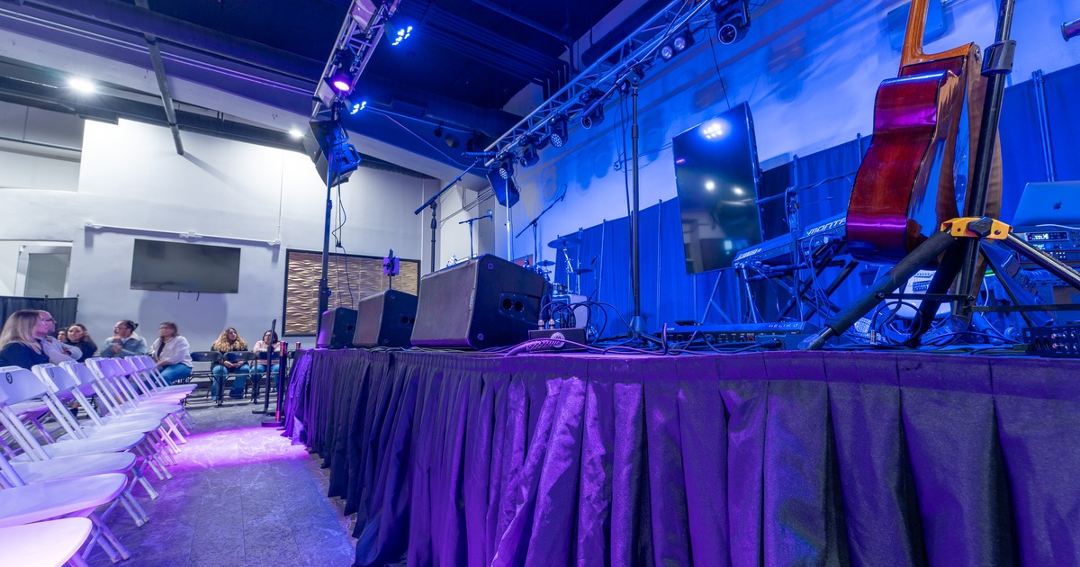 Stage setup with instruments and blue lighting. and seating space with chairs in rows.