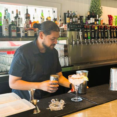 man behind bar making margarita.