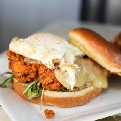 Fried chicken sandwich topped with white cheddar and egg