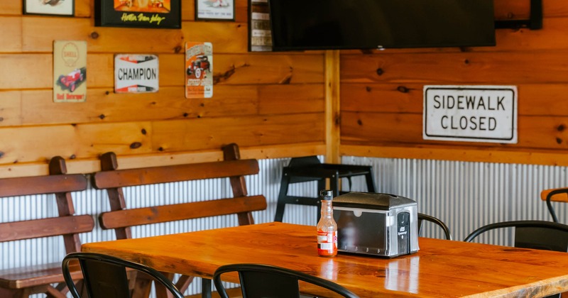 Rustic interior - wooden walls, vintage signs, a wooden table, black chairs, a flat-screen TV