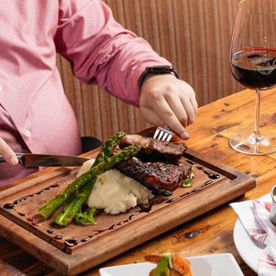 Hands eating a steak.