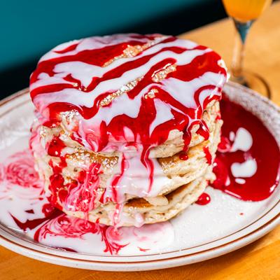 Tall pancake stack with strawberry icing drizzle.