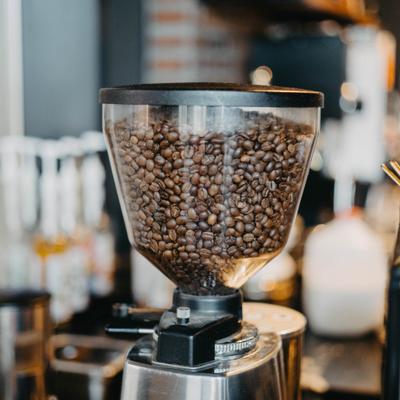 Commercial coffee grinder filled with roasted coffee beans.