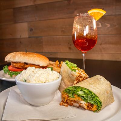 Buffalo Chicken Wrap served alongsiode Cod Sandwich and a cocktail.