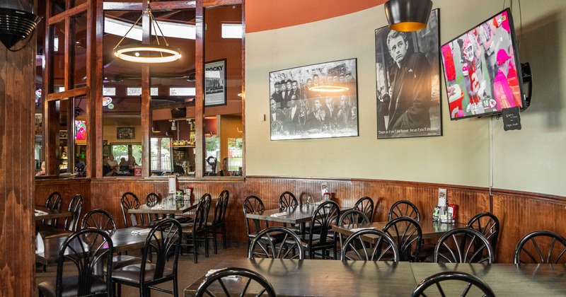 Interior, tables and chairs near wall with pictures and TV