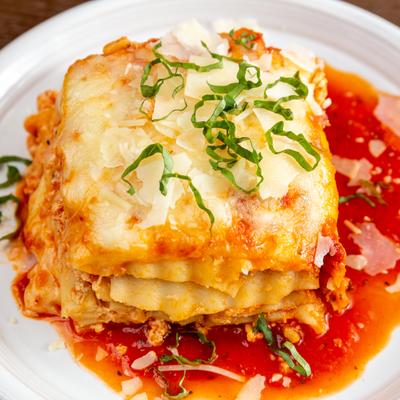 Lasagna topped with grated cheese basil, and tomato sauce.