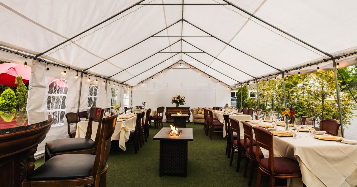 Covered seating area with tables, chairs, a fire pit, and string lights