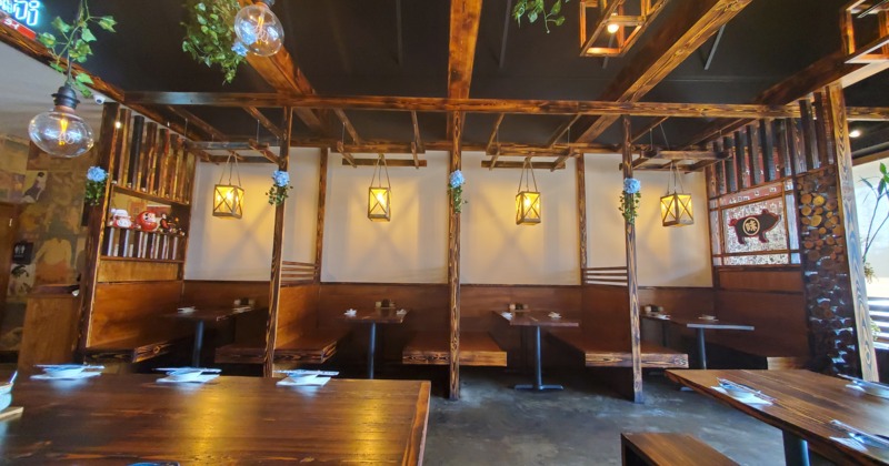 Dining area with wooden booths and tables under a ceiling of wooden beams